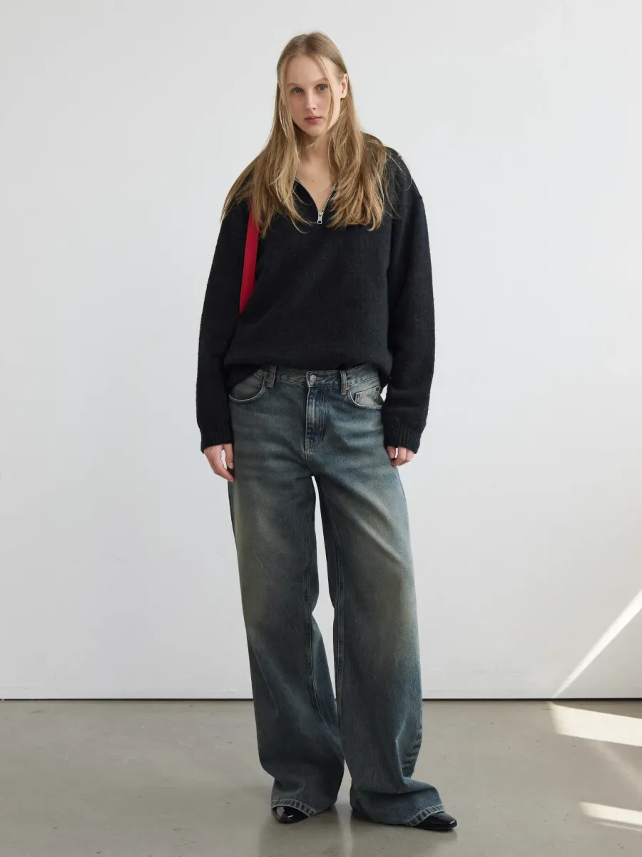Final imagery: the chosen model in a black half-zip knit and wide-leg jeans