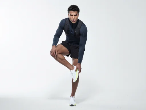 Model in athletic wear crouching against a soft grey backdrop