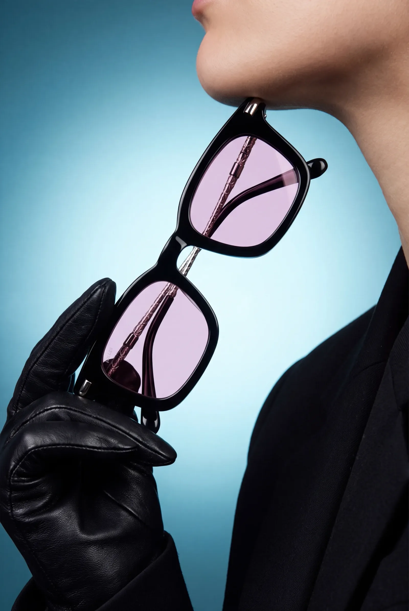 The sunglasses held up in a black leather glove beside the model’s chin